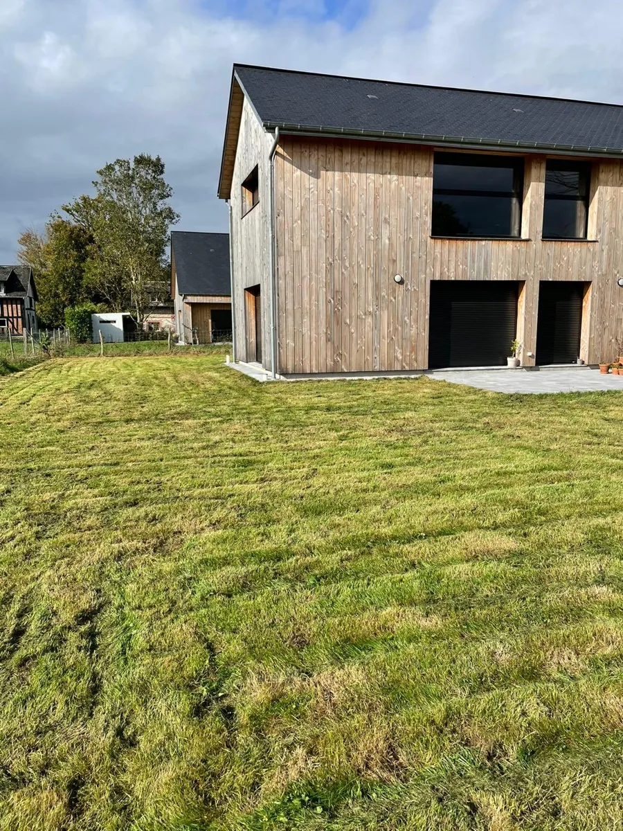 Pelouse tondue devant une maison à bardage bois